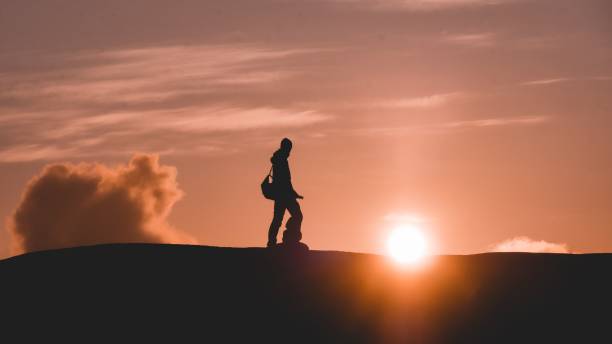istock Silhouette of a male with a backpack against beautiful sunset 1442113580