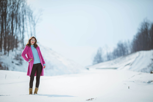 A shallow focus shot of a female wearing fashionable winter clothes in the snow