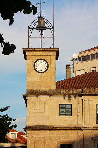 Town Hall in O Carballiño, Ourense province, Galicia, Spain. Clock and bell  tower close-up, clear blue sky at dusk.