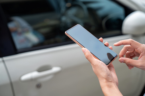 Cropped image of an Asian woman using mobile app device on smartphone to unlock the car doors