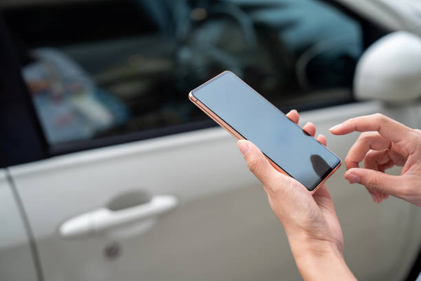 Close up person using mobile app device on smartphone to unlock car doors stock photo