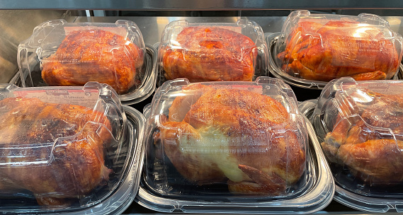 Several Rotisserie cooked whole chicken in plastic containers