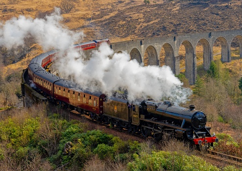 Glenfinnan, United Kingdom – July 20, 2022: A steam train passing over Glenfinnan Viaduct on the West Highland Line in Glenfinnan