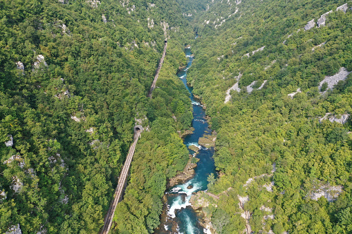 An aerial shot of a water stream surrounded by forests in Strbacki buk, Bosnia and Herzegovina