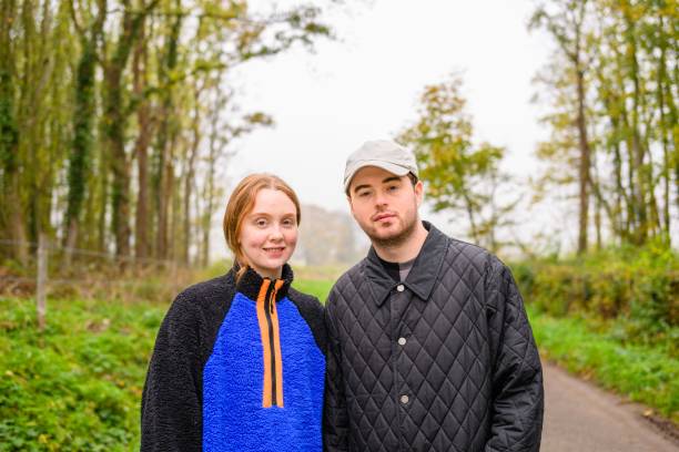 primo piano di un maschio e una femmina caucasici in posa sulla strada circondata da alberi verdi - cothing foto e immagini stock