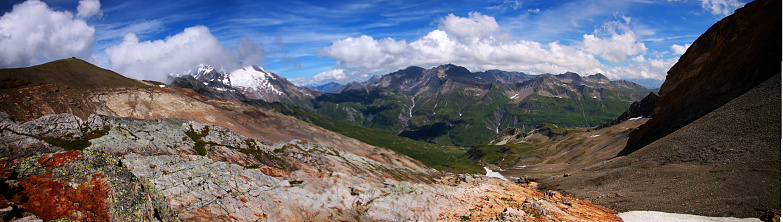 A panoramic shot of a landscape with mountains and a cloudy sky