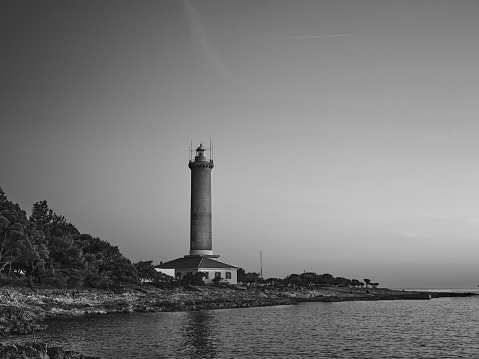 A grayscale shot of a lighthouse on the seashore