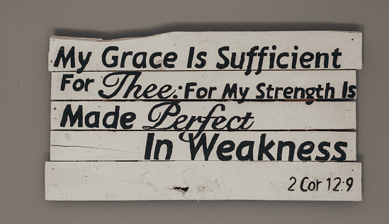 A closeup shot of a bible quote written on the white wooden signboard
