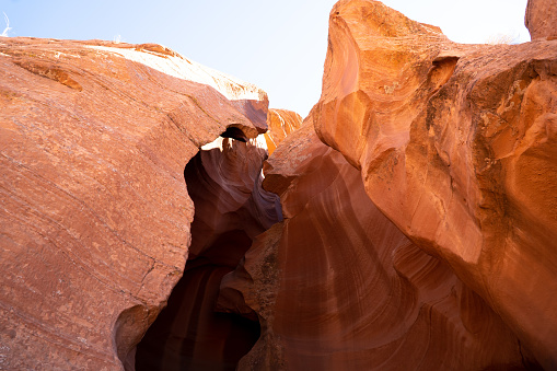 Nestled within the desert of Northern Arizona, Antelope Canyon exhibits the sheer beauty that nature can create. Famous for its lavish colors, unique patterns and complex textures, this slot canyon is a geological wonder that mesmerizes all who venture into its depths.  Carved into the red sandstone of the Navajo Nation, the canyon comes alive with a vibrant spectrum of reds, oranges, and yellows. The sunlight filtering through the narrow openings above casts an ever-changing, warm glow on the smooth, curving walls, creating a surreal play of shifting light and dancing shadows.  The rock formations within the canyon walls bear the unmistakable marks of time and weather. Millennia of wind and water erosion have sculpted the sandstone into flowing, sinuous shapes, creating a sensory experience that is as tactile as it is visual. Touching the canyon's surface connects a person directly to the forces of wind and water that have shaped it over countless millennia.  Antelope Canyon is in Coconino County near Page, Arizona, USA.