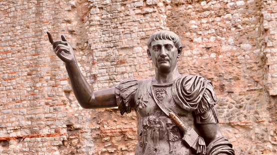 London, United Kingdom – February 08, 2018: A statue of Roman Emperor Trajan with remains of London Wall which was first built by the Romans in the 2nd and 3rd Centuries AD.