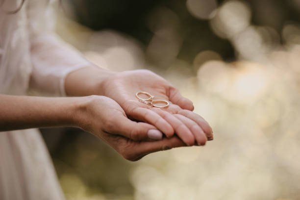 istock Bride holding the wedding rings in her palm with a bokeh background 1442117011