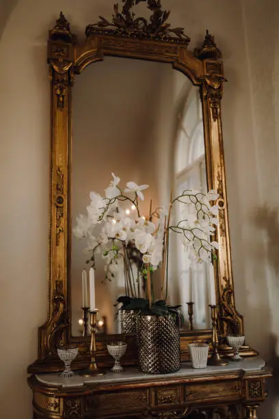 A vertical shot of flowers in front of the vintage-style mirror