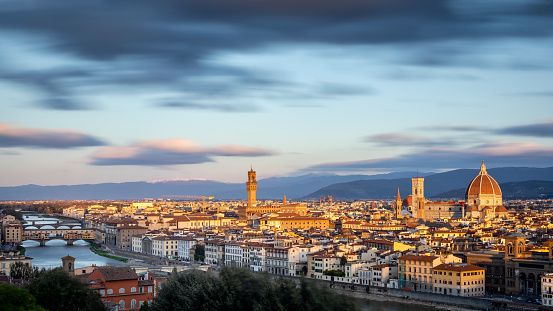 an aerial shot of Florence, Italy with a river and buildings under the clouds