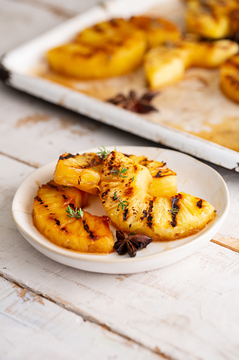 A selective focus shot of grilled pineapple slices with honey and cinnamon on a wooden table
