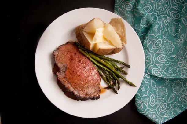 organic prime rib roast dinner with baked potato and asparagus