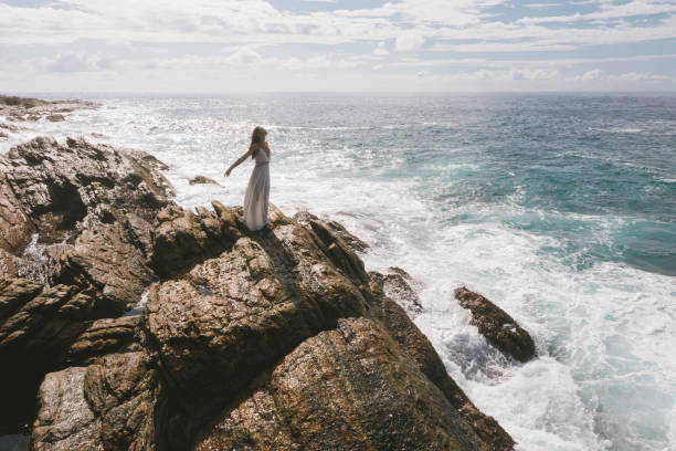 海の背景にロマンチックな花嫁、白いウェディングドレスを着たブルネットの女の子 - god freedom arms raised high angle view ストックフォトと画像