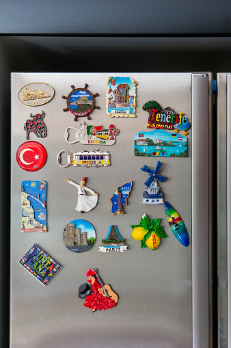 Poznan, Poland – July 22, 2018: A vertical closeup shot of magnetic gift souvenirs from different countries attached to the fridge