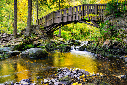 A wooden bridge over the Oker river with large stones on Engagement island in the Harz Mountains,
