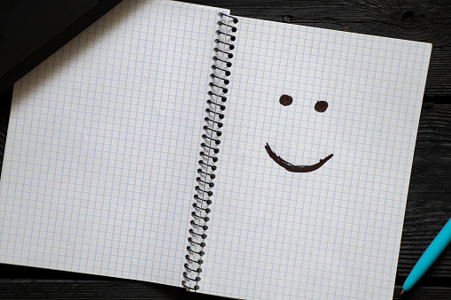 a smile drawn in a notebook on a desk during work, a good mood