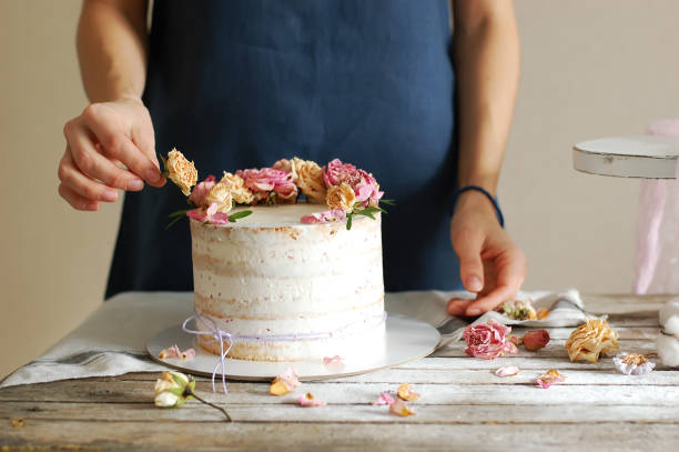 istock Woman's hands decorate the cream cake with fresh flowers 1442123550