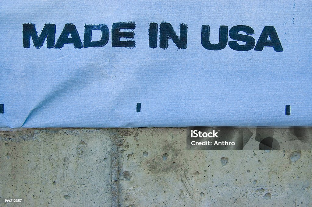 Grungy Made in USA Made In USA stamped on the exterior wrapping of a new home under construction.  Textured concrete of the foundation contrasts the wrapping. American Culture Stock Photo
