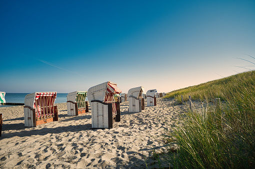 Timmendorf beach,  Germany, Europe- June 20,2023: Beach baskets at Timmendorfer Strand with Seeschloesschenbruecke and Japanese teahouse, Luebeck Bay, Baltic Sea