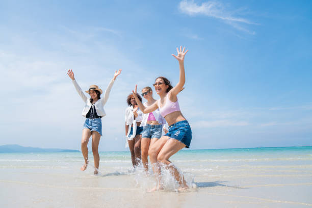 Happy friends at beach party runs together on the beach having fun in a sunny day stock photo