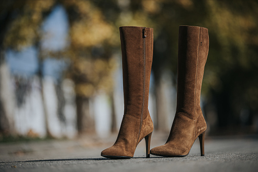 A fashionable brown suede knee-high boots outdoors