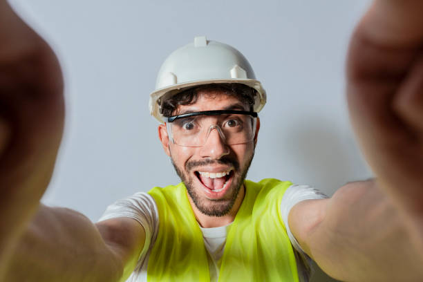 lächelnder männlicher ingenieur, der ein selfie mit blick in die kamera macht. lustiger bauingenieur, der isoliert ein selfie macht, ingenieur, der isoliert ein selfie macht. ansicht eines männlichen ingenieurs, der isoliert ein selfie macht - attractive male men humor looking at camera stock-fotos und bilder