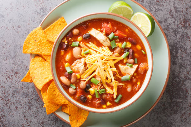 istock Chicken Taco Soup with black bean, corn kernels, tomatoes topped with cheddar cheese in green bowl, horizontal top view 1442134185