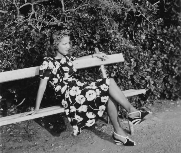 istock Beautiful young woman sitting on a bench. 1938. 1442138277