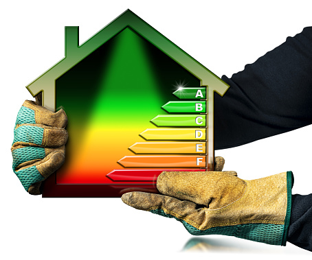 House energy efficiency rating. Manual worker wit protective work gloves holding a small model house with the Energy Performance Chart. Isolated on white background. Photography  and 3D illustration.