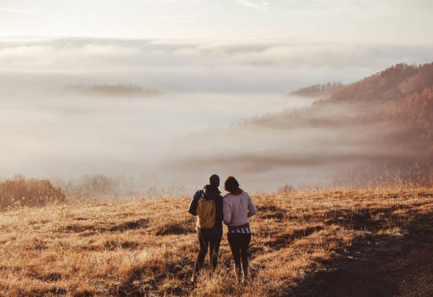 Young couple enjoying on hill in countryside at sunrise stock photo