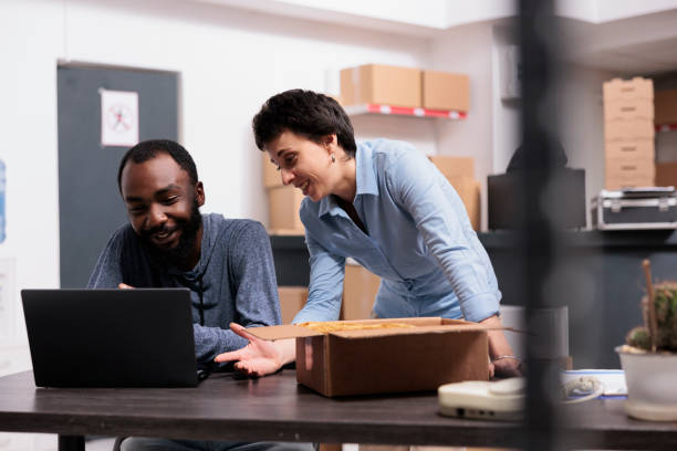 istock Workers finising packing trendy blouse while checking retail drop shipping package on laptop computer 1442143952