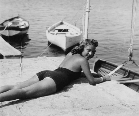 Beautiful young woman wearing swimwear on vacation in tourist resort. 1938.