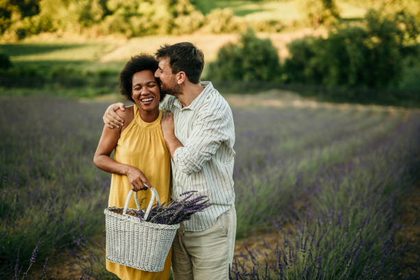 Photo of a smiling diverse couple in a countryside field. enjoying the beautiful and peaceful weekend getaway, far from the hustle of the city.