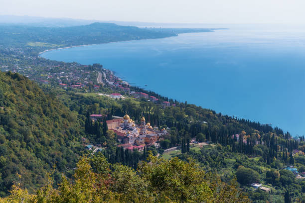 View of the ancient New Athos Monastery (Abkhazia) from the top of the mountain in summer. A popular place among tourists and pilgrims. Gradually recovering and getting better. Cypress garden.