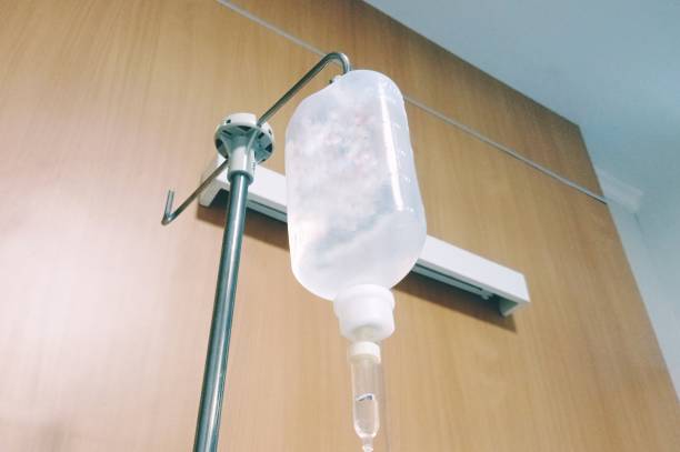 istock Saline Drip Hanging on Metal Hook Against Wall in Hospital 1442154162