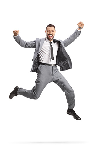 Excited young businessman in a grey suit jumping isolated on white background