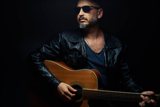 istock Guitarist on stage. Man playing guitar in a dark environment 1442159705