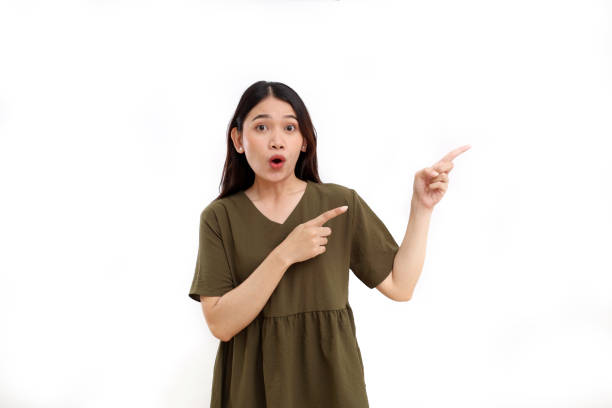 istock Wow and amazed expression of young asian woman while pointing something beside her. Isolated on white 1442160166