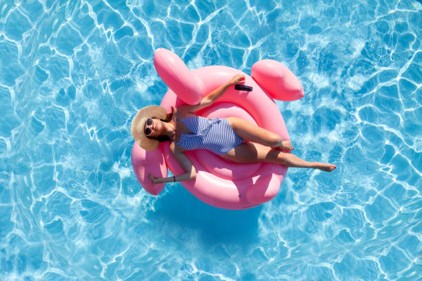 woman relaxing on pink flamingo inflatable ring - bikini summer vacations looking down imagens e fotografias de stock