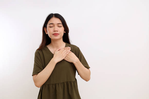 istock Beautiful young asian woman standing while holding her chest. Relieved, peaceful feeling concept 1442162185