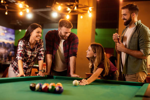 istock Group of friends having fun while playing pool in a local pool hall 1442163399