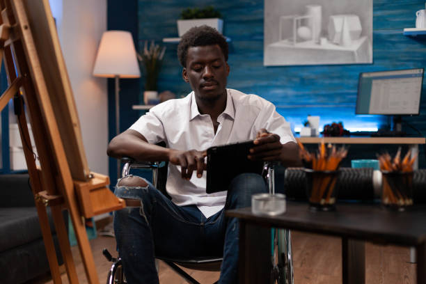 istock Young man in wheelchair holding tablet computer 1442164660