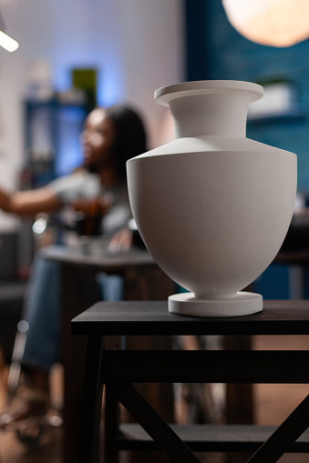 Selective focus on vase standing on table for artist inspiration in art atelier. Young illustrator with disability sketching draw using professional graphic pencil working at creative masterpiece