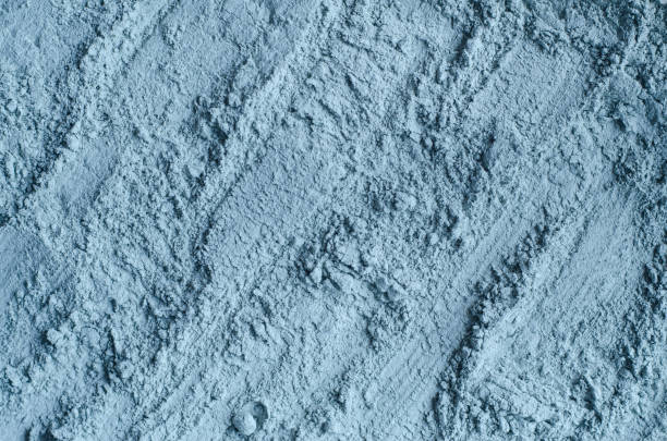 Blue bentonite facial clay powder (alginate modeling mask, eye shadow, body wrap) texture close up, selective focus. Abstract background with brush strokes.