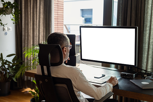 Middle age man working on computer at home, white screen mockup.