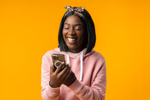 istock Happy african girl using her smartphone against yellow background. 1442172672