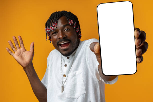 istock Excited young african man holding smartphone with white blank screen in hand on yellow studio background 1442172757